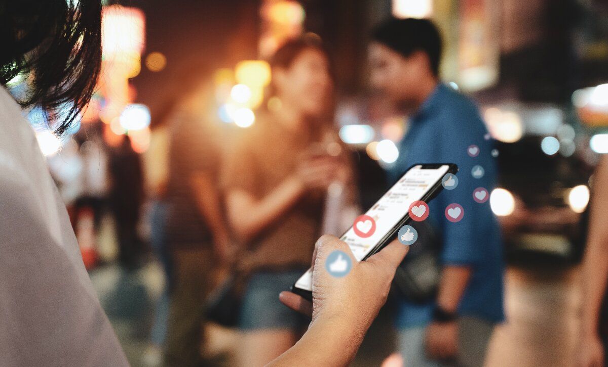 Social Media Reputation: Junge Frau blickt auf das Smartphone in ihrer Hand