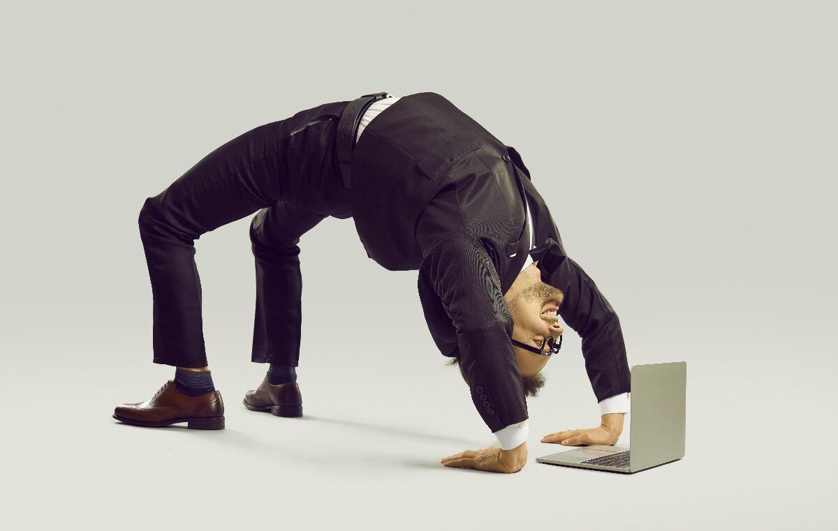 Flexibler Geschäftsmann in Yoga-Pose vor Laptop