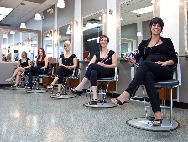 Mehrere Frauen sitzen auf Stühlen in einem Friseursalon.